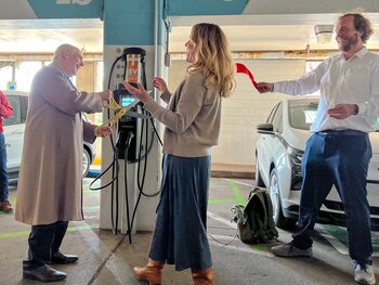 Three people happily cutting ribbon