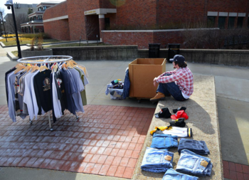 Student kneels next to clothing rack